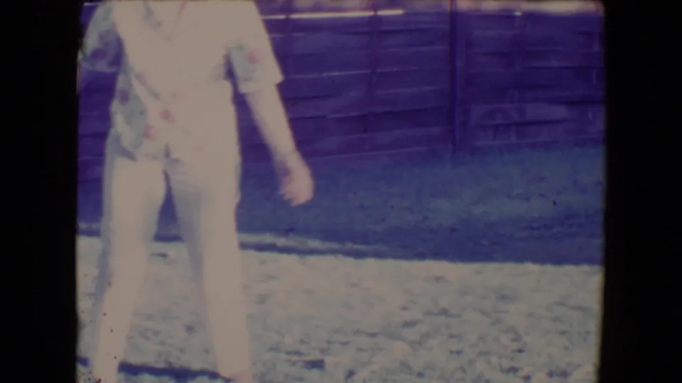 The woman is partly cropped in a 1967 backyard frame, with grass and a wooden fence filling the background.