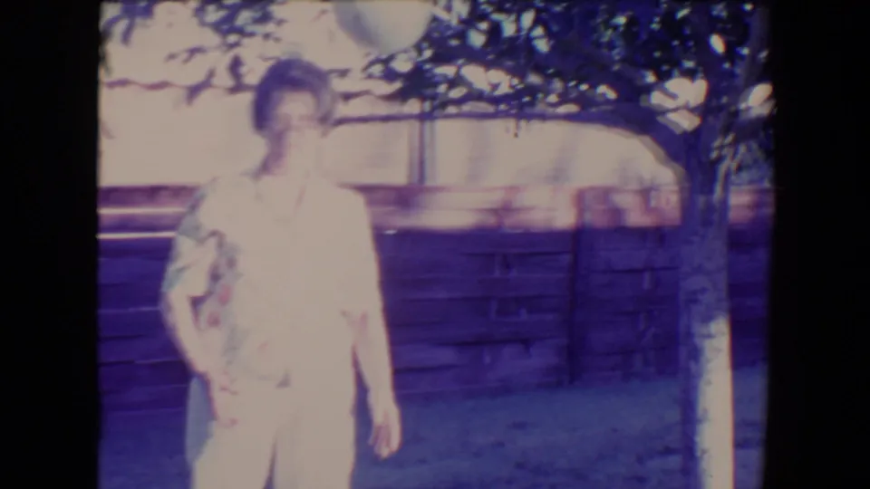 Woman looks upward under tree branches as the pale ball rises above her in the supplied 1967 Tucson backyard scene.