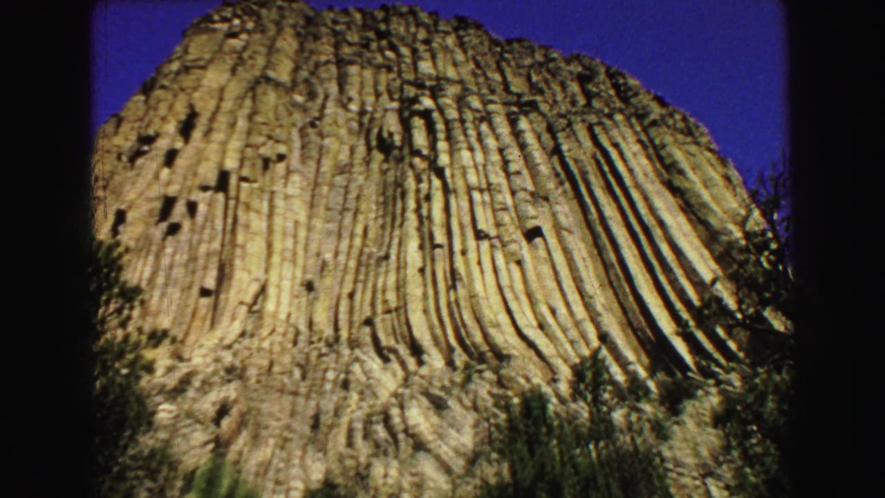 Low-angle view of a columned rock formation beneath a deep blue sky.