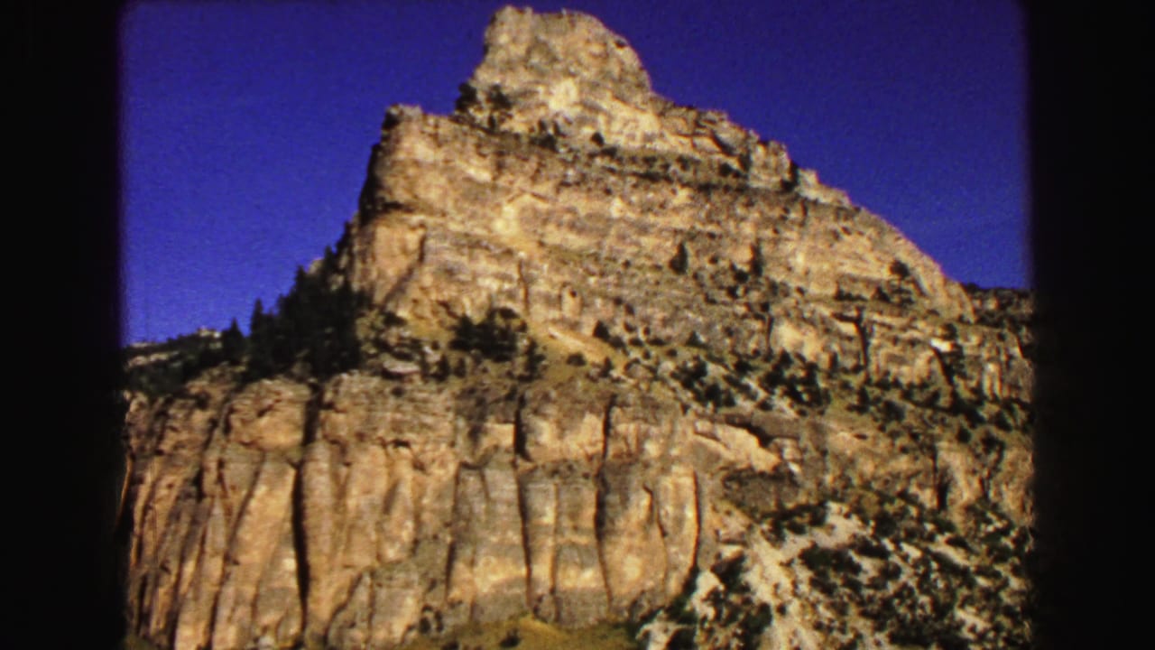 Sunlit layered rock formation beneath a deep blue sky.