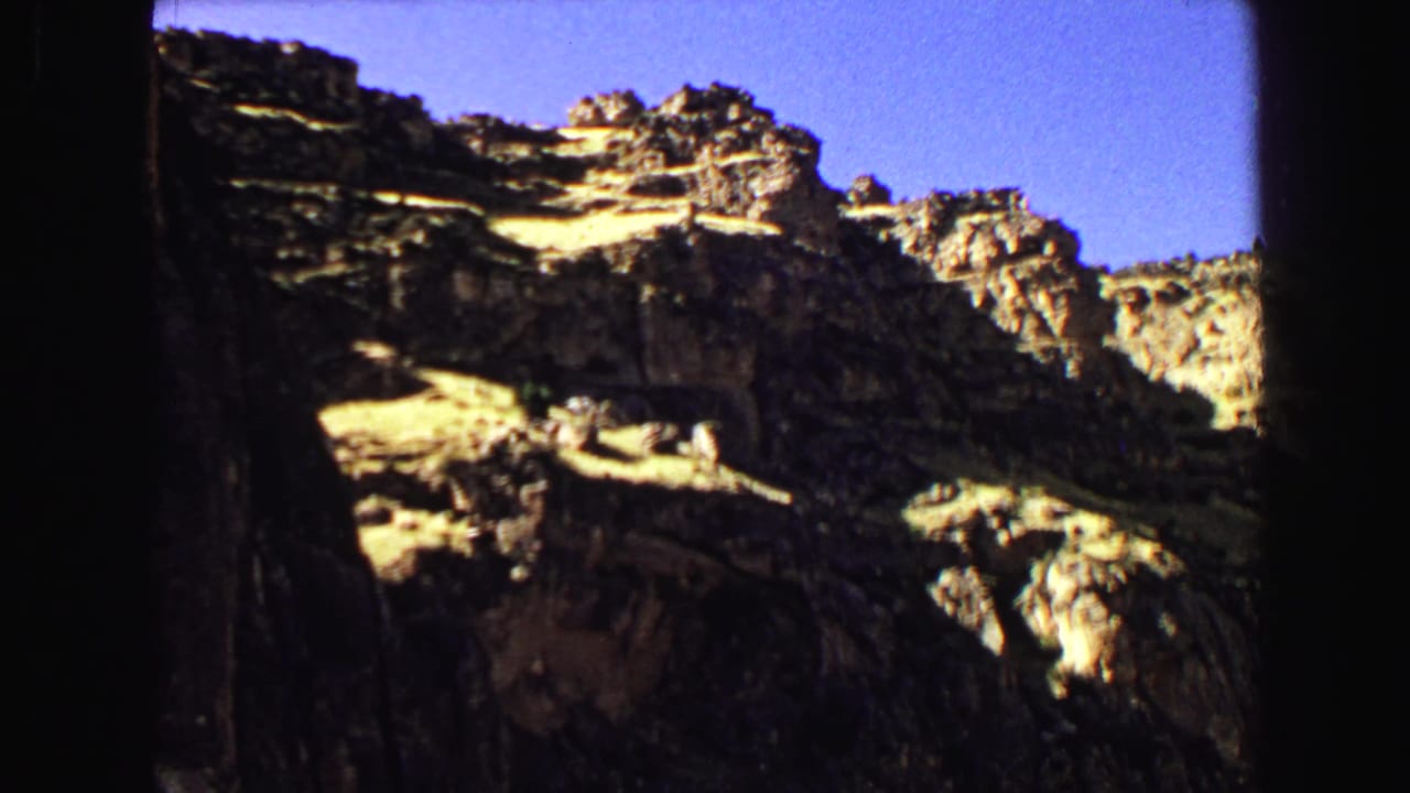 Shadowed mountain rock face with bright sky above.