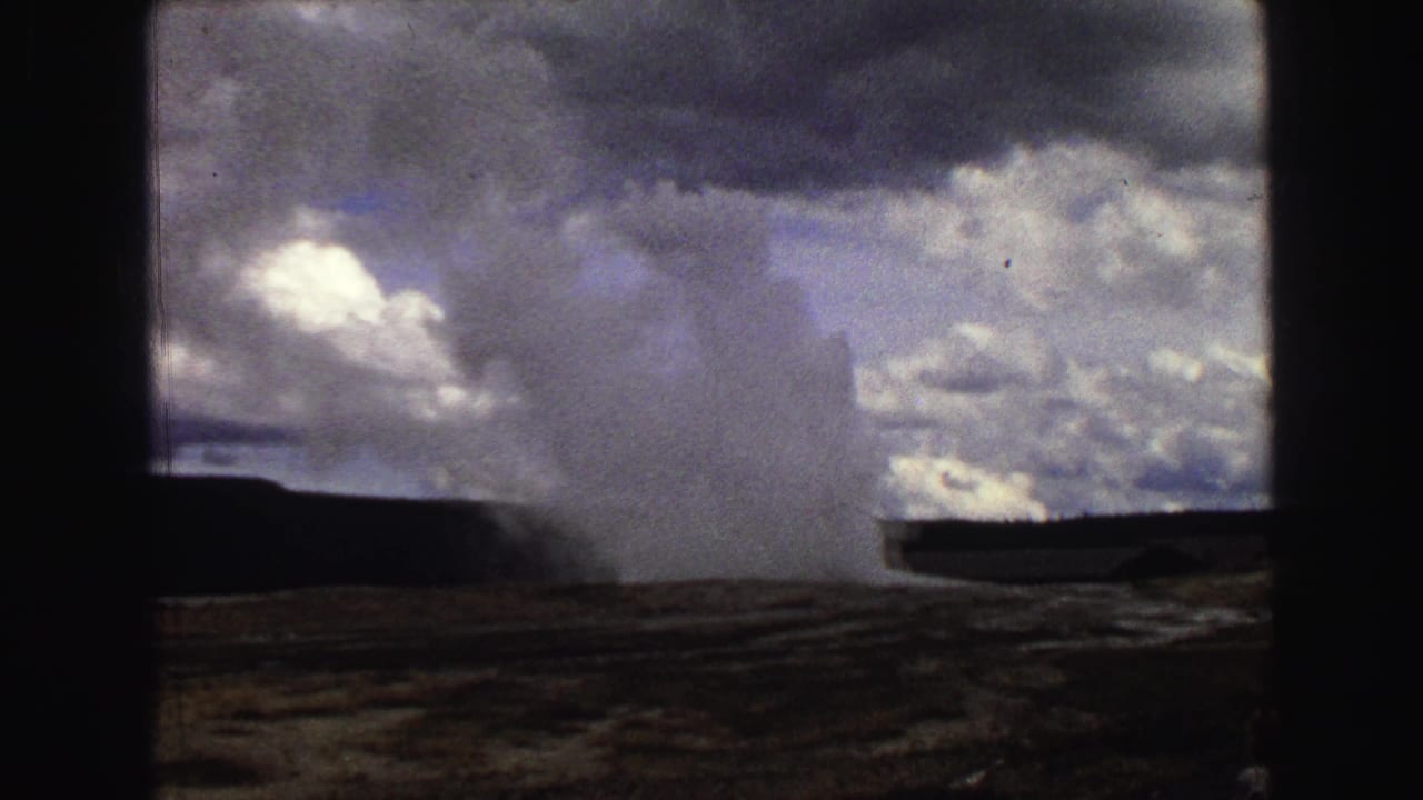 Old Faithful geyser plume rising under a cloudy sky with dark frame edges.