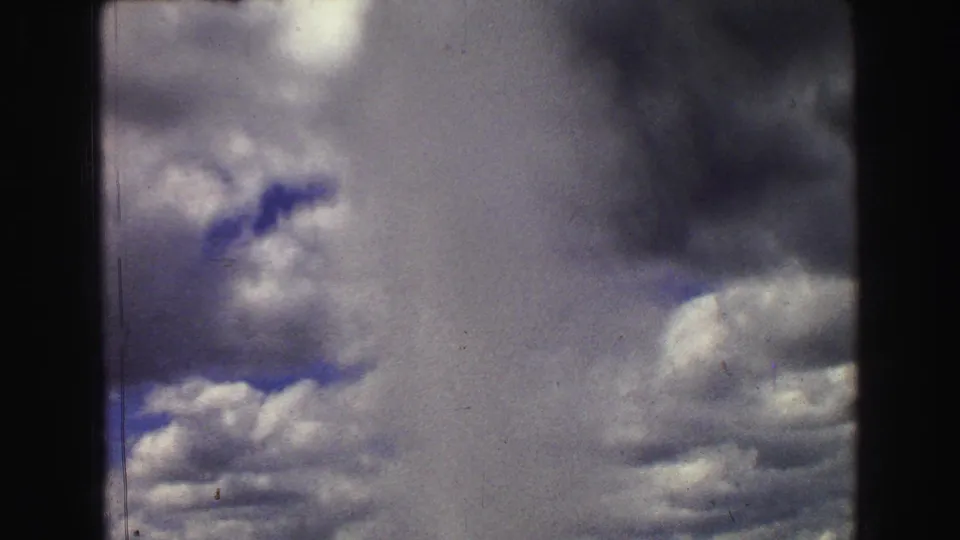 Old Faithful's plume fills the 1967 Yellowstone frame, with soft 8mm grain and clouds behind the spray.