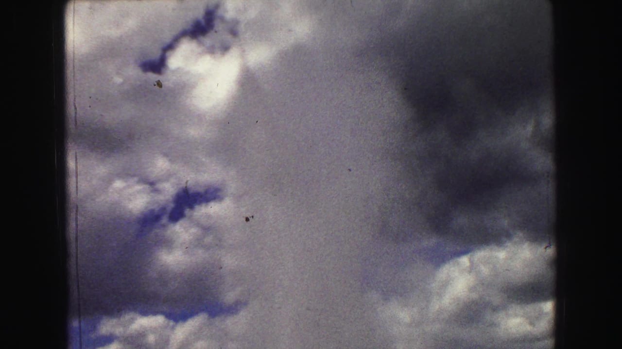 Cloudy sky with dark film borders and visible 8mm grain.