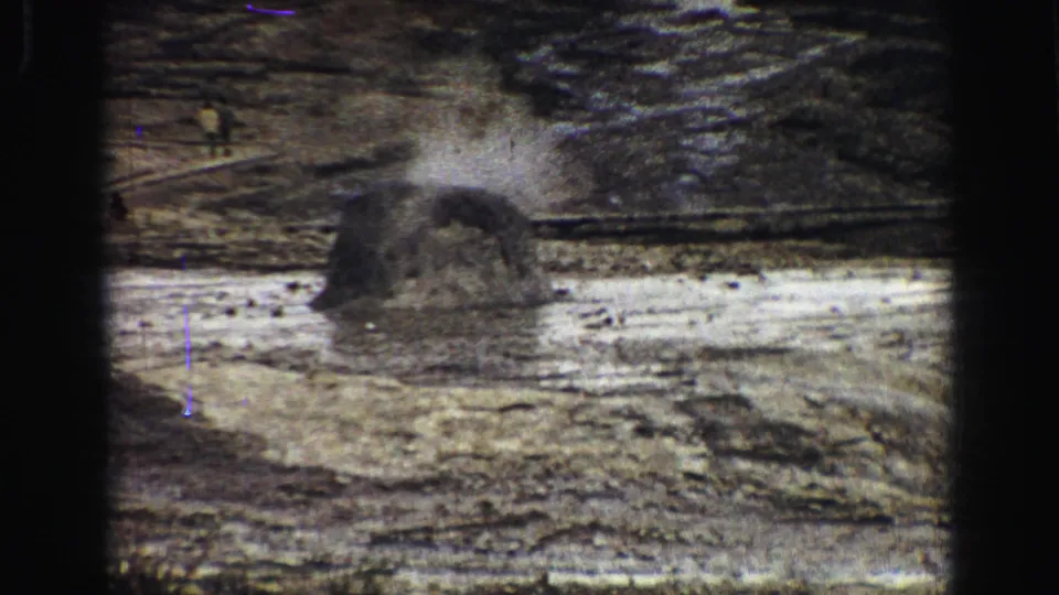 1967 8mm Yellowstone frame with a low geyser vent releasing steam over textured mineral ground.