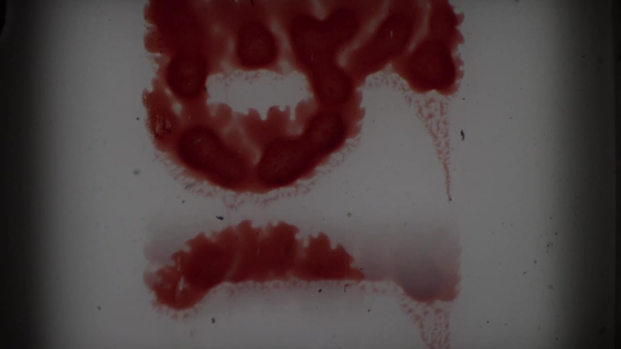 Red film marks and staining over a pale film frame.