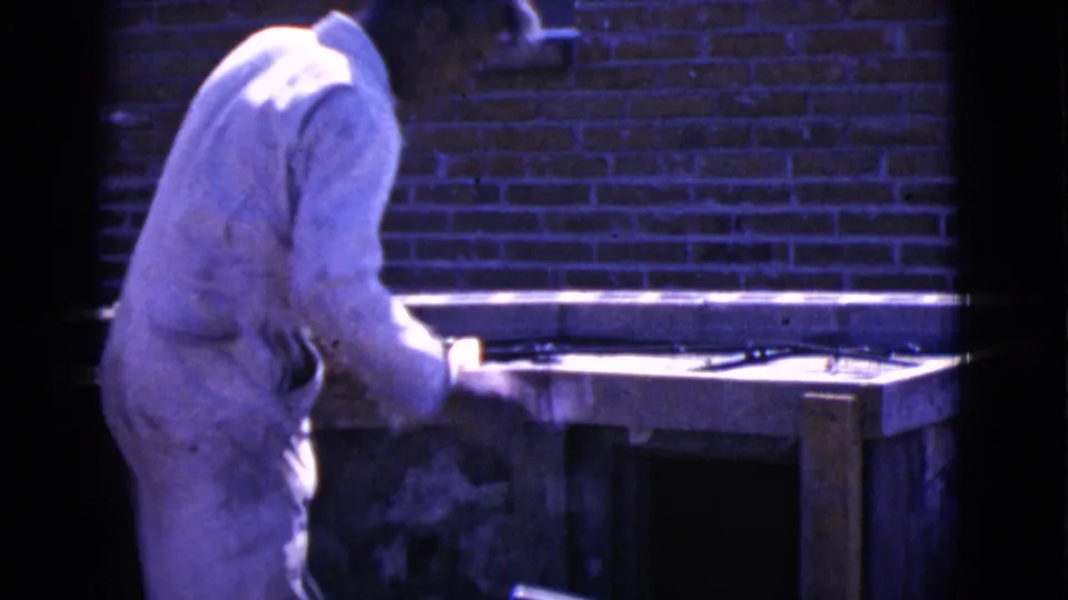 In Cottonwood, Arizona in 1968, a man in white work clothes works beside a wood form and mortar against a red brick wall.