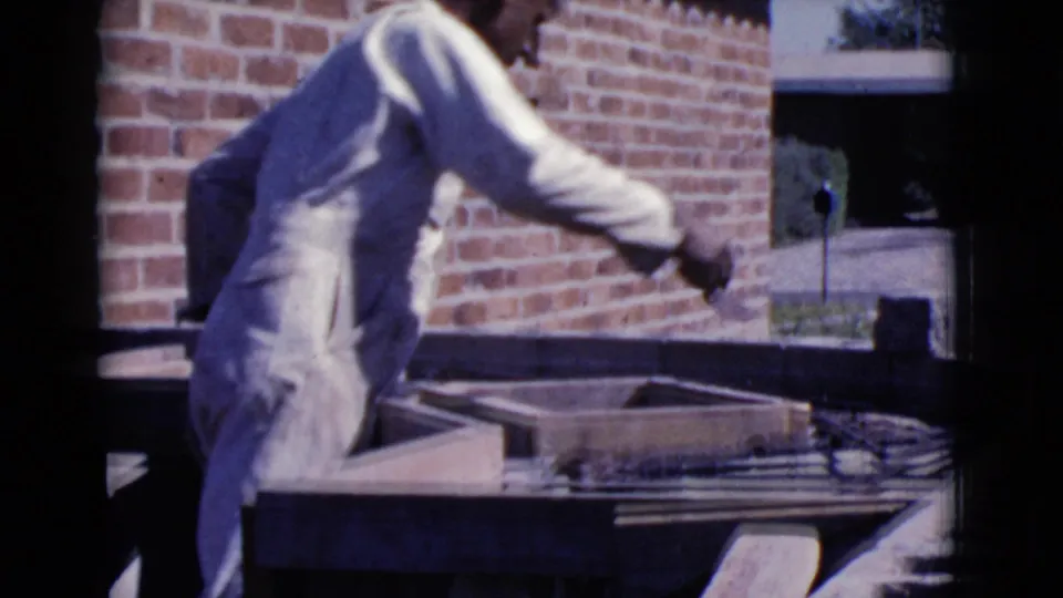 The 1968 Cottonwood, Arizona footage shows a man bending over a wood form while preparing mortar for brickwork outdoors.