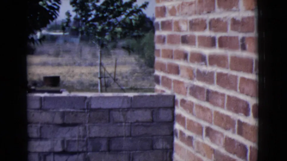 The final frame shows the brick construction area and yard after the worker has moved mostly out of view in the Cottonwood, Arizona footage.