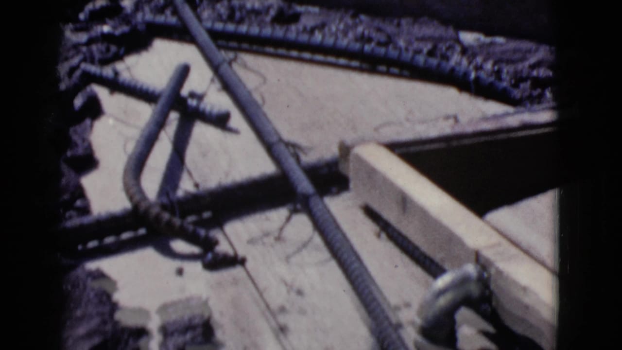 Wooden framing, rebar, and scattered construction materials on rough ground.