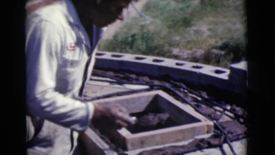 A man in a light shirt handles materials around wooden forms and rebar in Cottonwood, Arizona, 1968.