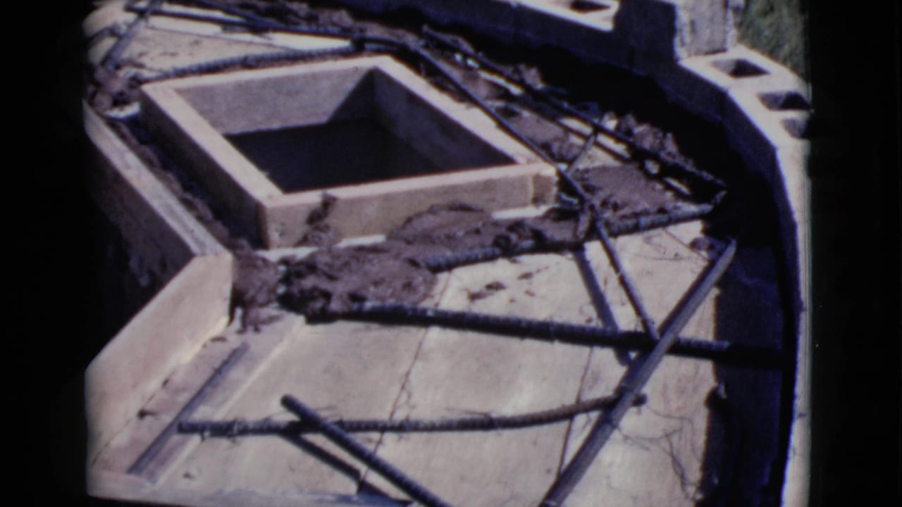 Concrete form with exposed rebar and cinder blocks on an outdoor construction surface.