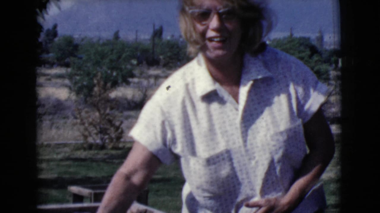 In 1968 Cottonwood, Arizona home-movie footage, a woman in sunglasses stands near a concrete block wall in a sunny yard.