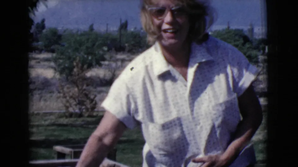 In 1968 Cottonwood, Arizona home-movie footage, a woman in sunglasses stands near a concrete block wall in a sunny yard.