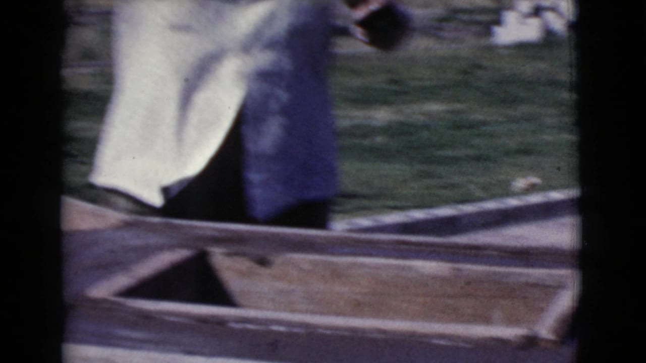 Partial view of a person near wooden boards in a sunny yard.