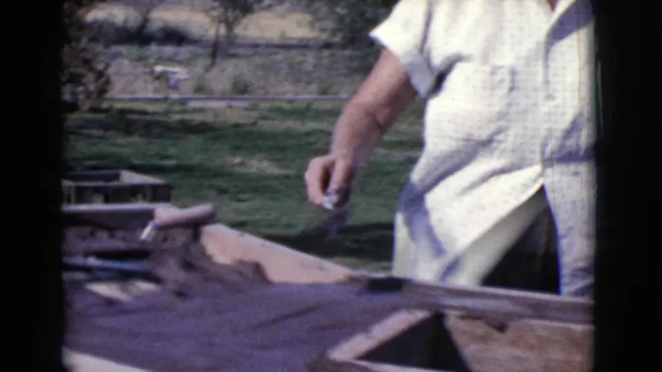 An adult in a patterned white shirt stands beside a sunlit masonry surface in the Cottonwood, Arizona home movie.