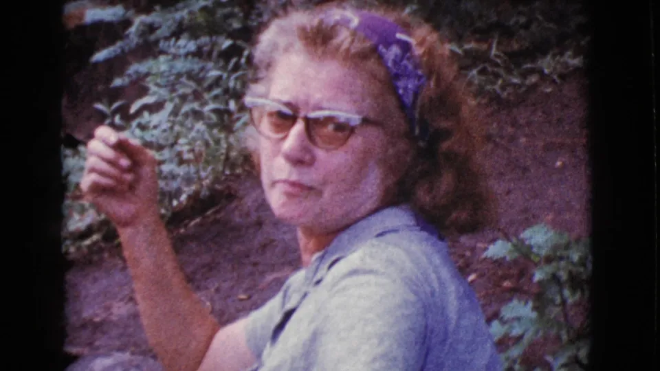 Adult woman in glasses and a light shirt looks slightly away from the camera near the wooded stream in Cottonwood, Arizona.