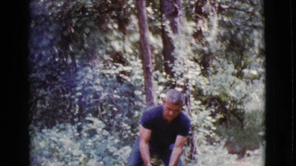 The man remains bent forward in a wooded Cottonwood, Arizona setting, with soft 8mm focus and filtered daylight.