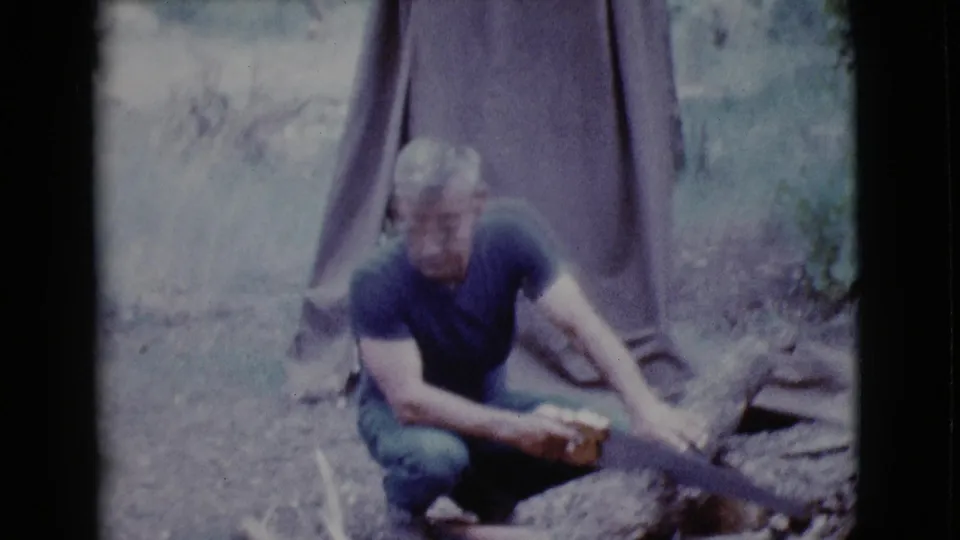 In the 1968 Cottonwood campsite footage, the man crouches near a canvas tent and continues cutting firewood by hand.