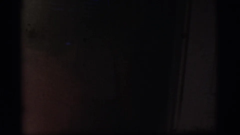 Mostly dark 8mm frame at the start of the Cottonwood, Arizona home-movie clip, with only faint interior shapes visible.