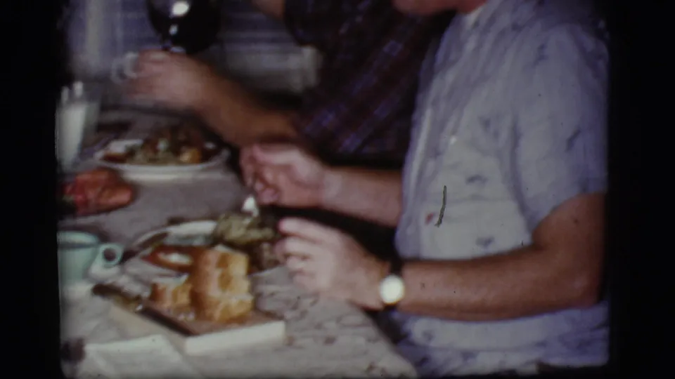 1968 Cottonwood, Arizona dining room scene with adult diners, a man in a light patterned shirt, plates of food, and milk glasses.