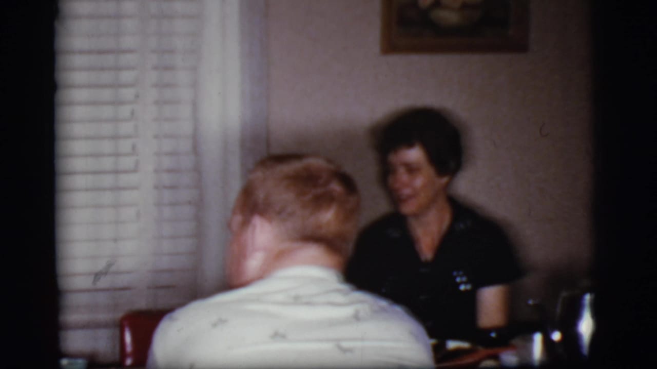 Adults seated around a dining table in a softly lit home interior.