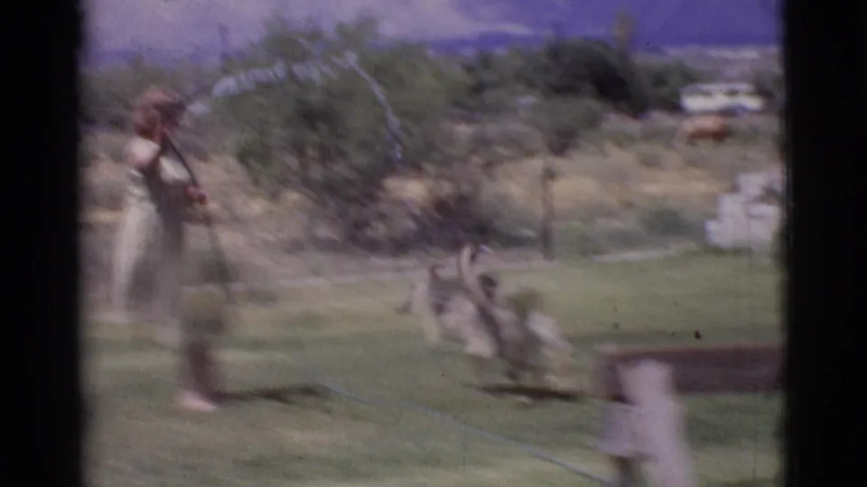 Motion blur from 8mm footage shows the woman watering while the dog darts near the water spray in Cottonwood, Arizona, 1968.