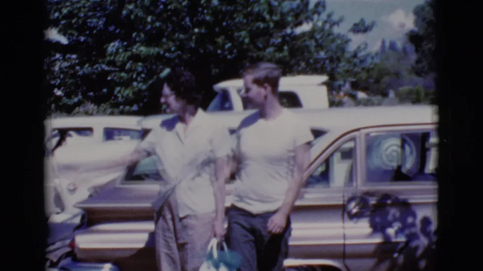 A Cottonwood, Arizona family outing moment shows a woman with purse and a man walking past vintage cars in 1968.