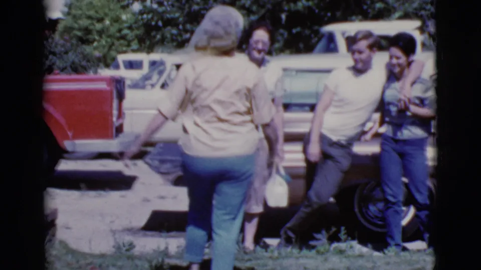 Adults in casual clothing gather near a red vehicle and light-colored cars in Cottonwood, Arizona, according to clip metadata.