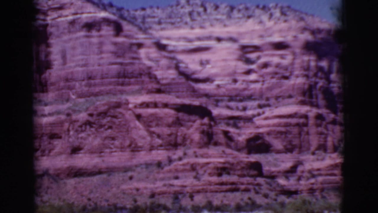 1968 8mm view near Cottonwood, Arizona, showing a red sandstone canyon wall with horizontal layers under blue sky.