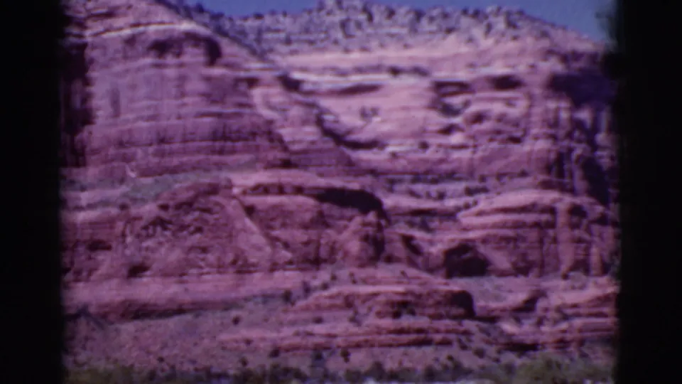 1968 8mm view near Cottonwood, Arizona, showing a red sandstone canyon wall with horizontal layers under blue sky.