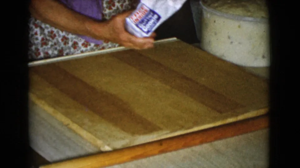 1968 Cottonwood, Arizona kitchen frame with a woman holding a labeled paper flour bag above a wooden work board.