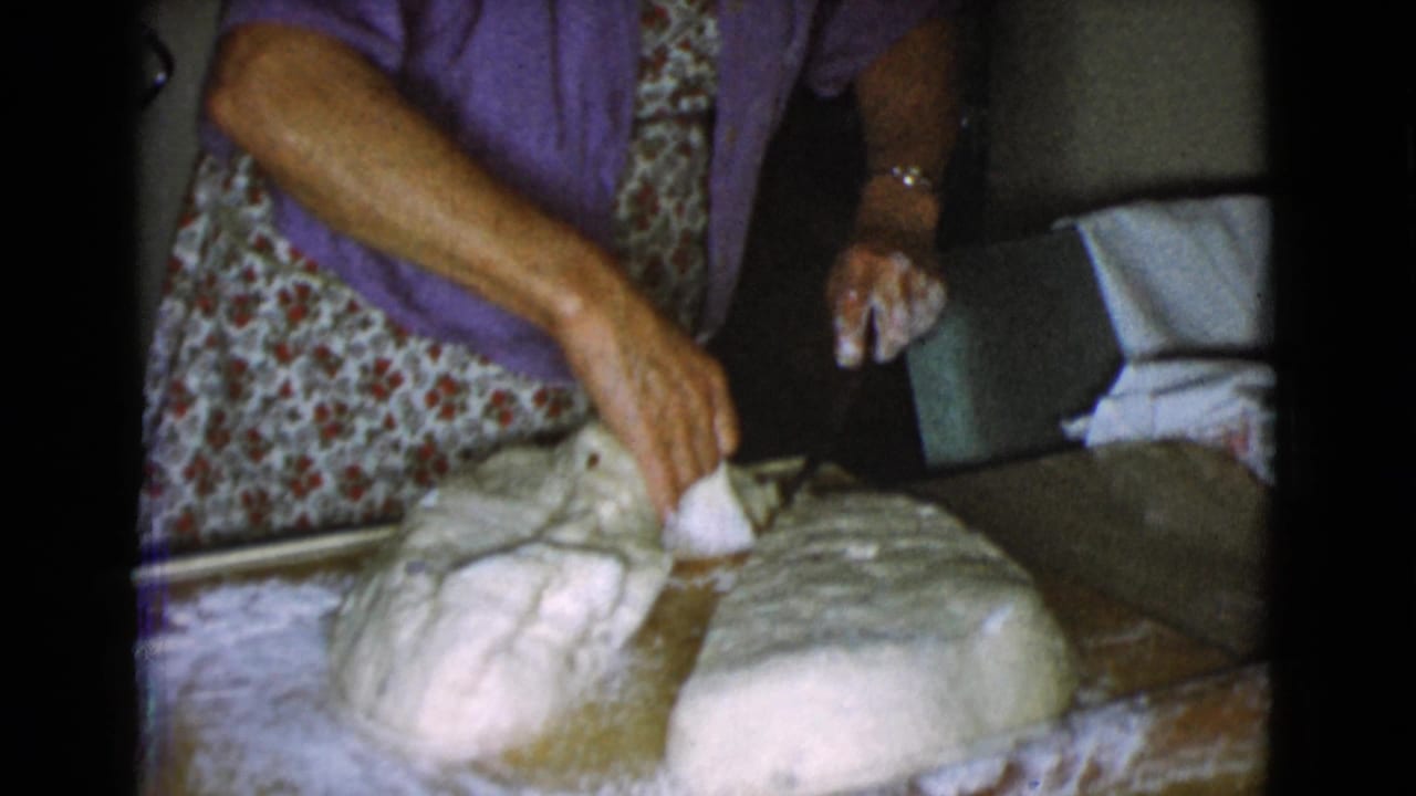 In a 1968 Cottonwood, Arizona home kitchen, a woman in a purple cardigan works dough on a floured surface.