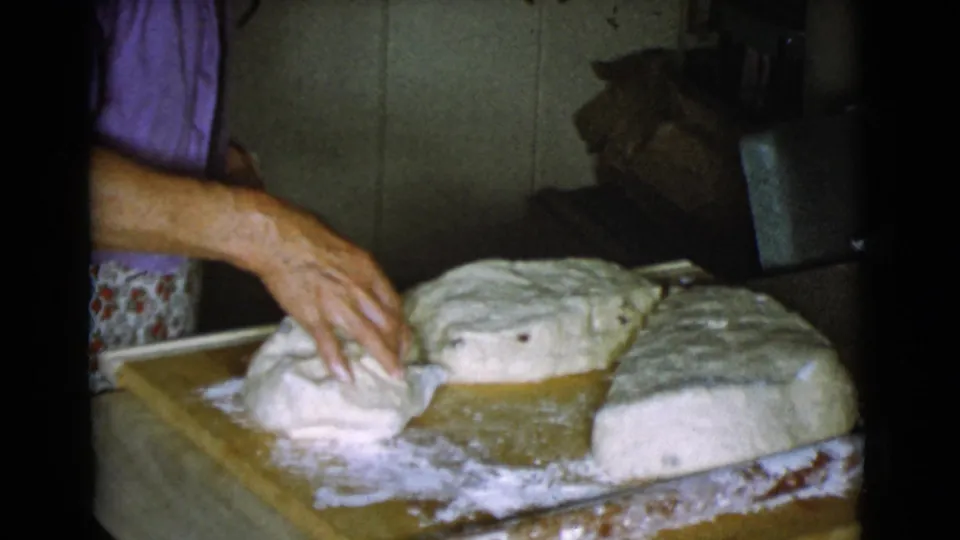 At the end of the clip, the woman's hand reaches over several dough pieces on a floured board in the 1968 kitchen footage.