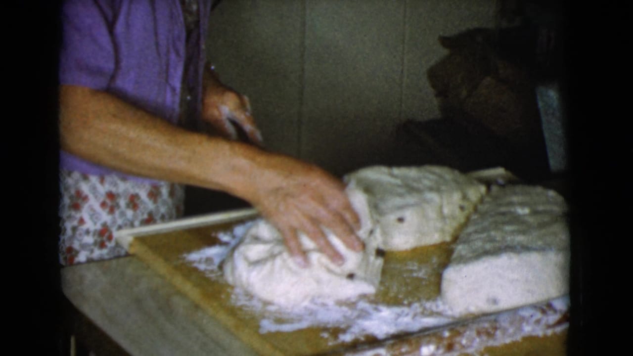Woman's hands shape bread dough on a floured wooden board.
