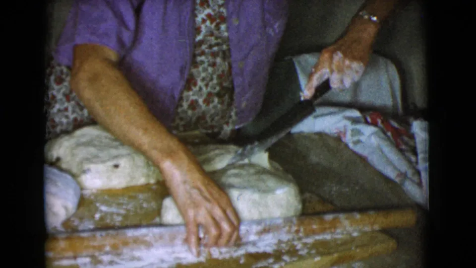 The woman holds a knife near divided bread dough on a floured wooden board in the Cottonwood, Arizona home kitchen.