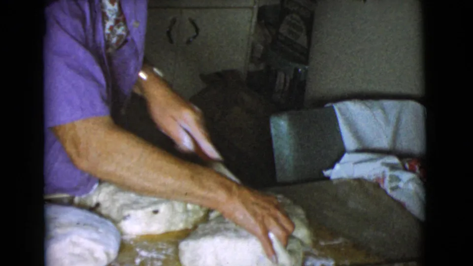 An elder woman's hands press and shape dough beside other portions in the Cottonwood, Arizona home kitchen footage.