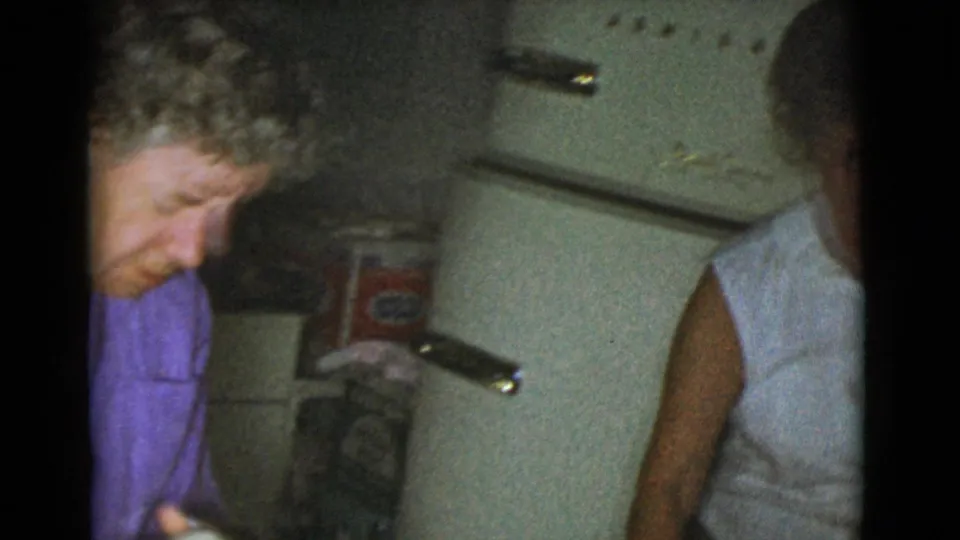 A home kitchen view shows the dough-making area shifting toward a rounded refrigerator and adults partly visible in the room.