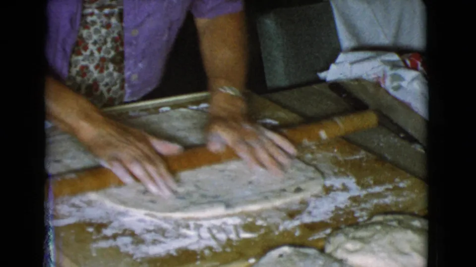 The rolling pin passes over a sheet of dough while flour is scattered across the wooden board in the 1968 home kitchen scene.