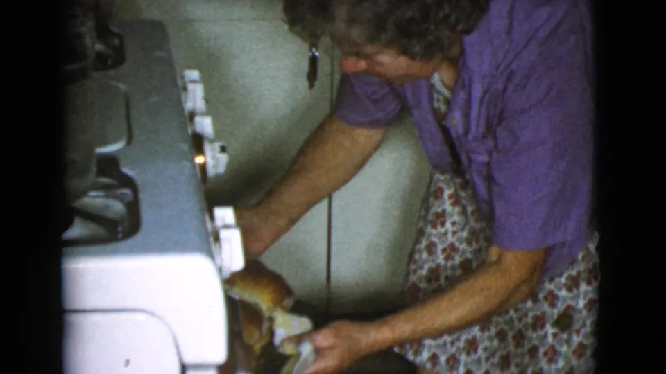 In the 1968 Cottonwood kitchen footage, the woman reaches beside the oven as a golden loaf comes into view.