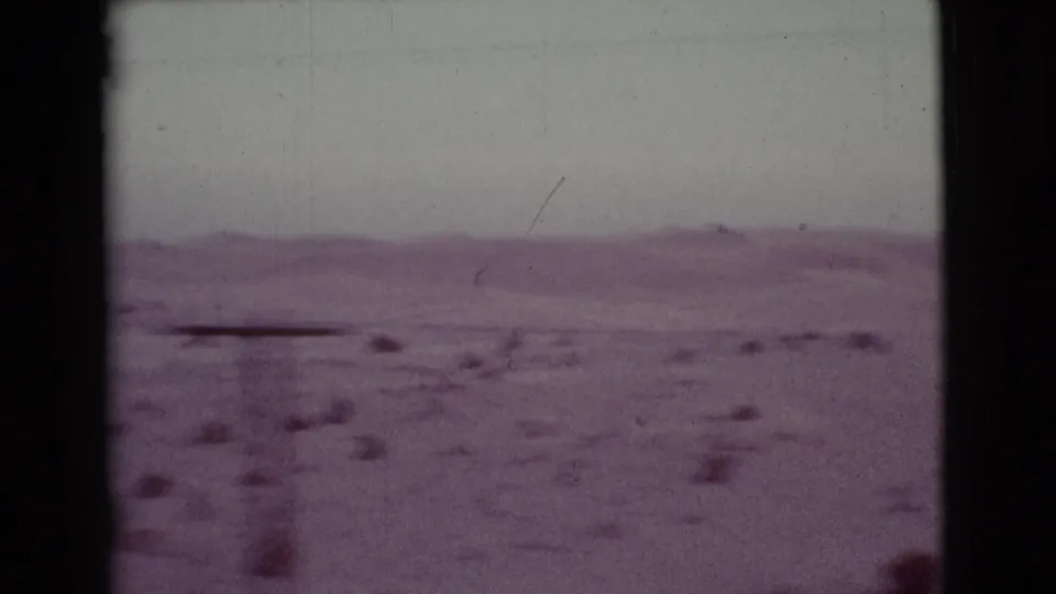 1968 Cottonwood, Arizona 8mm frame showing open desert, low distant hills, pale sky, and scattered brush from a moving viewpoint.