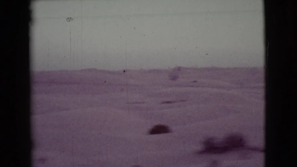 1968 Cottonwood, Arizona 8mm frame showing a low horizon, open desert ground, scattered shrubs, and soft purple-tinted film texture.