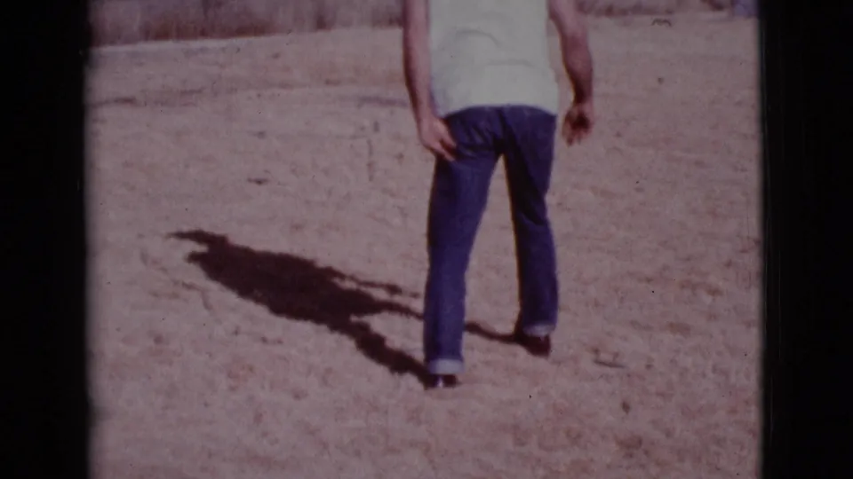 An adult man in a light shirt and dark pants stands on sandy ground in the 1968 Cottonwood, Arizona home-movie footage.