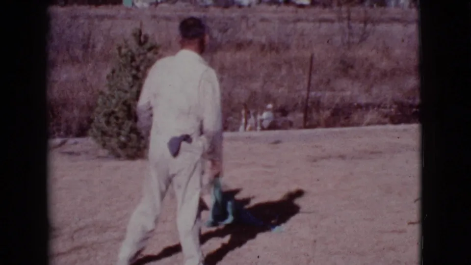 The man turns away in the dry Cottonwood yard while the German Shepherd stays close to the teal towel.
