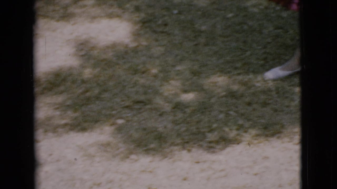 Lower yard view with grass, dirt patches, and part of a white shoe at frame edge.
