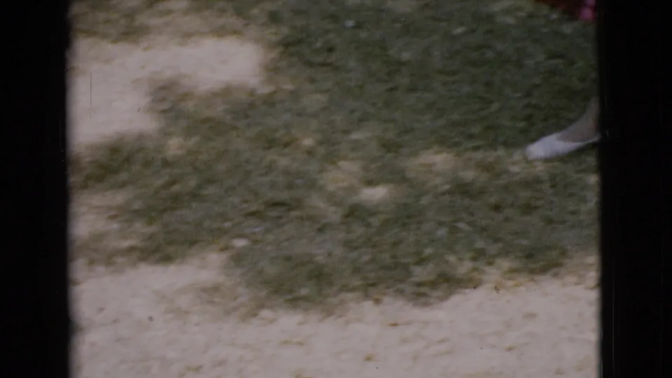 1968 Cottonwood, Arizona home-movie frame showing a grassy yard with dirt patches and a partial white shoe near the edge.