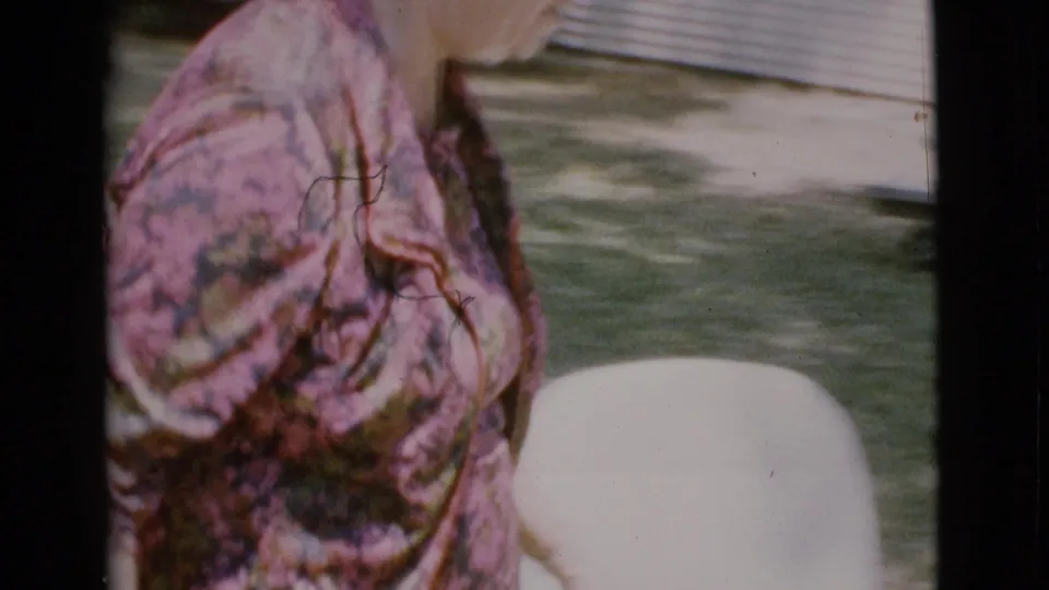 Elderly woman in a pink-green floral dress walking outdoors in Cottonwood, Arizona home-movie footage from 1968.