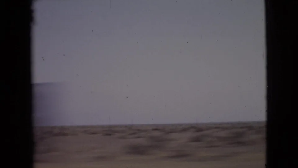 San Diego County roadside terrain in 1968, with low scrub and faint hills seen through the 8mm frame.