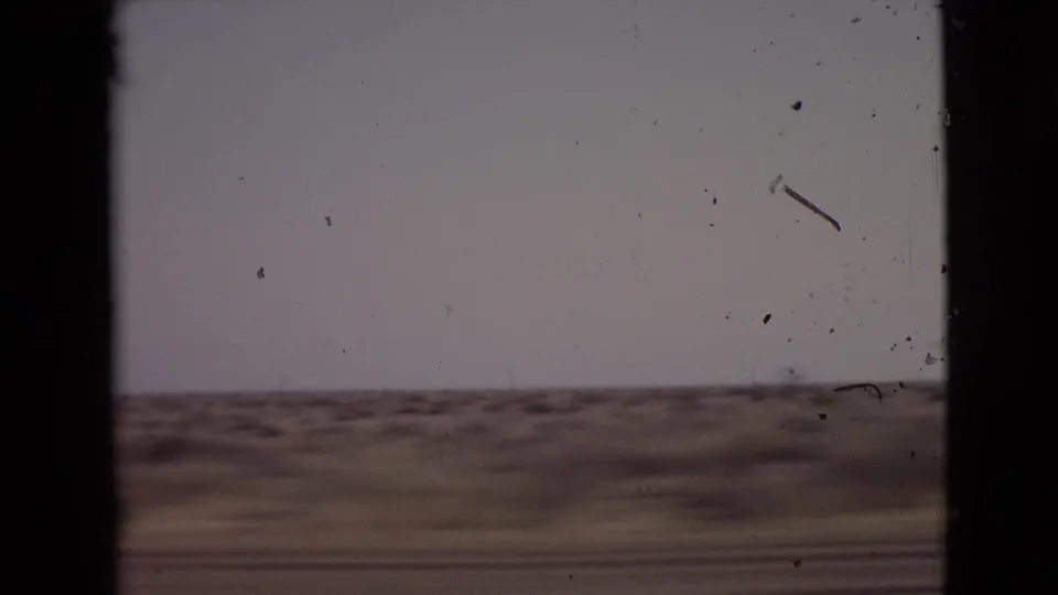 Moving-vehicle 8mm view of sparse San Diego County roadside vegetation and open horizon in 1968.
