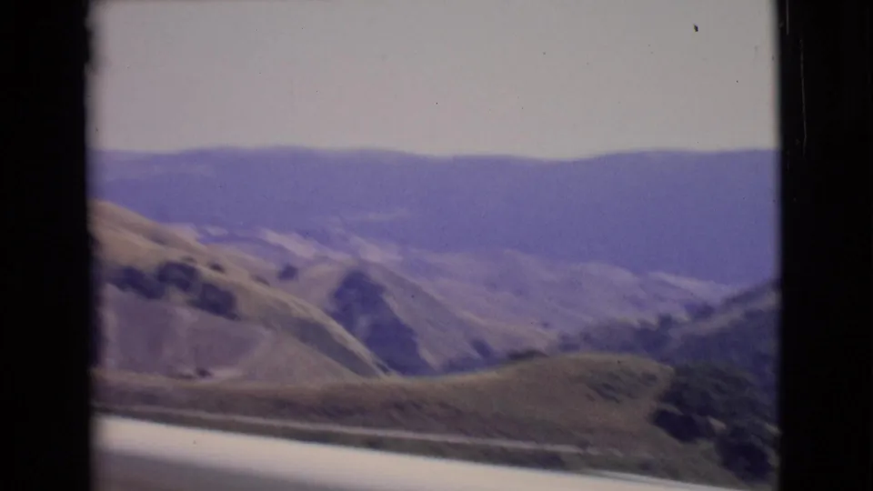 1968 San Diego County landscape frame with open hills, valley contours, and blue distant ridges softened by haze.